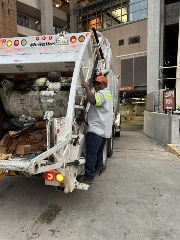 Quincy Styles, an SWR worker, rides on a trash truck heading under DKR-Texas Memorial Stadium after a home football game.