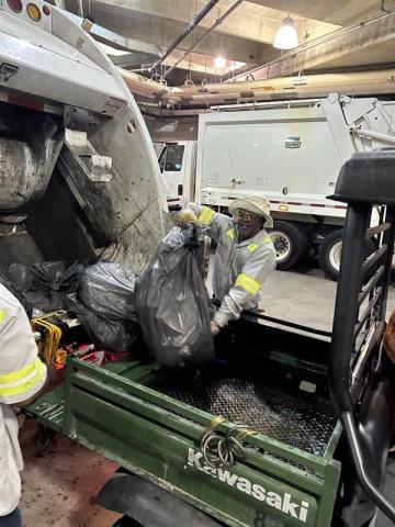 Damon Moseley, an SWR driver, unloads a golf cart full of trash into the back of an SWR refuse truck on Sunday morning during the stadium clean-out.