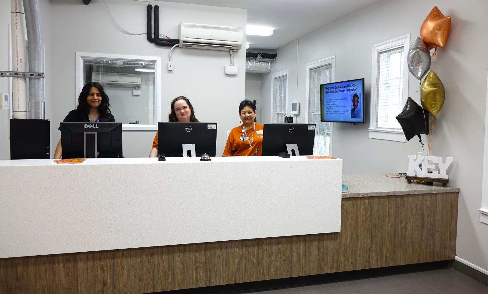 Three Lock and Key Services employees smiling behind the service counter. 